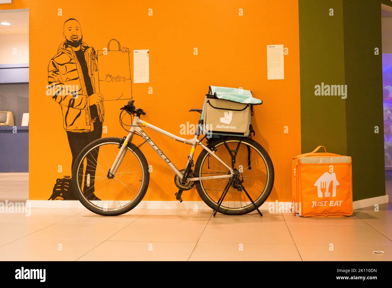 Deliveroo-Rückentasche, die an einem Lieferfahrrad im Migrationsmuseum in Lewisham befestigt ist Stockfoto