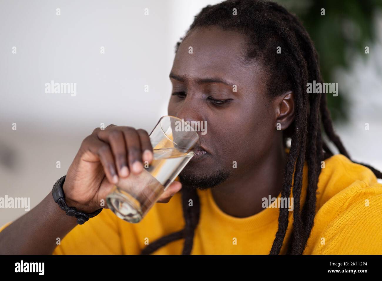 Körperhydratisierung. Junger Schwarzer Mann Mit Dreadlocks, Die Wasser Aus Glas Trinken Stockfoto
