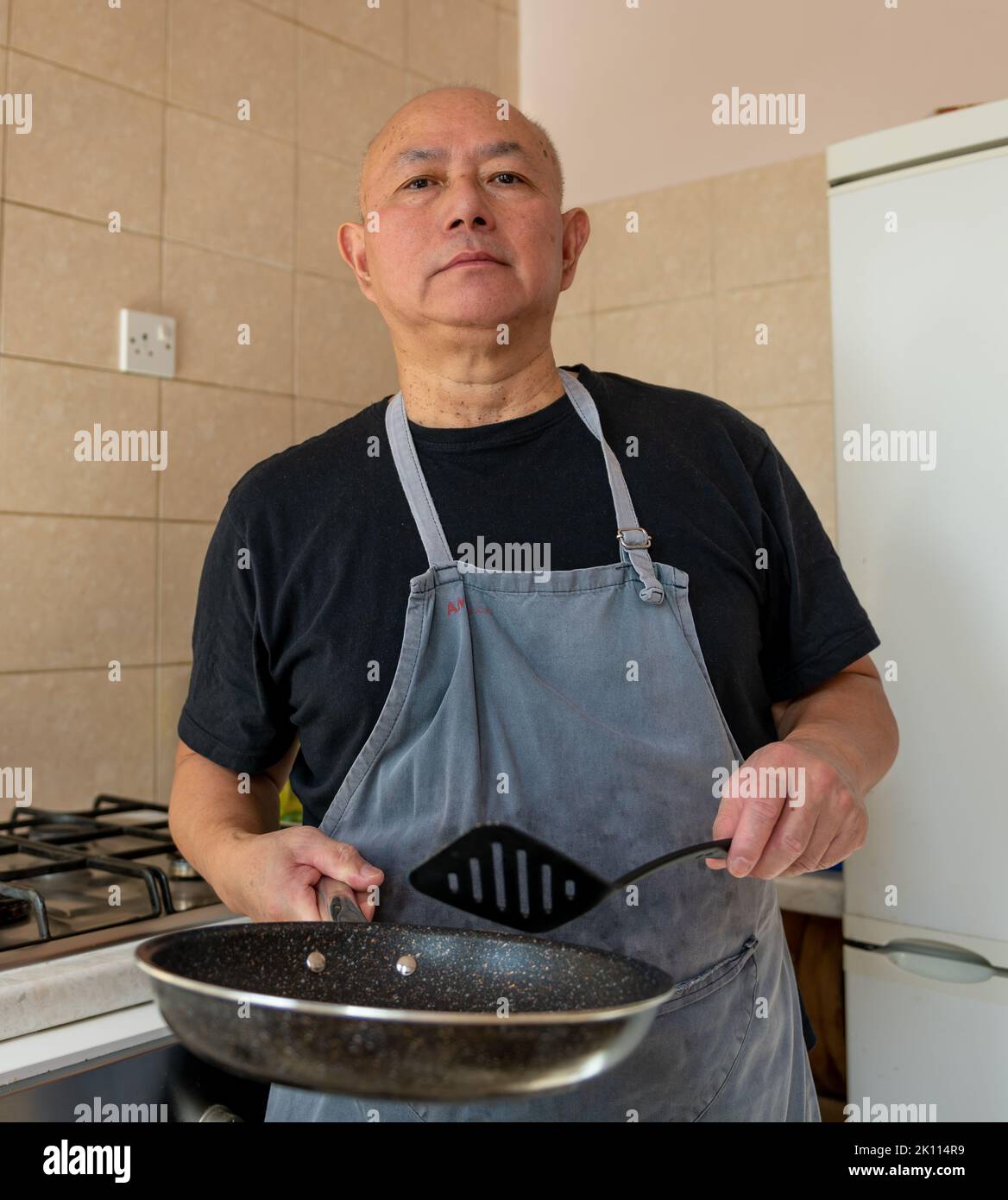 Portrait eines älteren Mannes, Koch, der in der Küche eine Mahlzeit zubereitet. Stockfoto