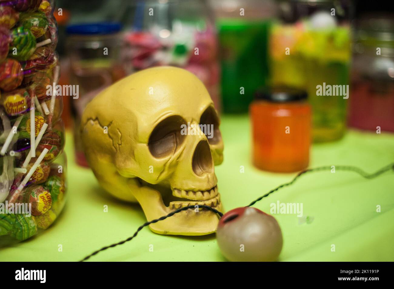 Nahaufnahme des Totenschädels mit Süßigkeiten und anderen Leckereien auf einer coolen Halloween Party im Innenbereich. Einfache und traditionelle Einrichtungsideen. Lustiger horizontaler Hintergrund. Stockfoto