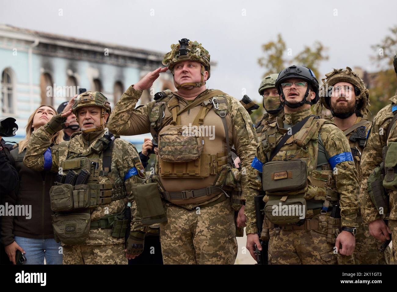 Izium, Ukraine. 14. September 2022. Ukrainische Soldaten grüßen, während die Nationalflagge während einer Zeremonie mit Präsident Wolodymyr Zelenskyy vor dem ausgebrannten Rathaus am 14. September 2022 in Izium, Region Charkiw, Ukraine, angehoben wird. Zelenski machte einen überraschenden Besuch in der Stadt, die während einer ukrainischen Gegenoffensive aus Russland zurück erobert wurde. Kredit: Ukrainisches Presidential Press Office/Ukraine Presidency/Alamy Live News Stockfoto