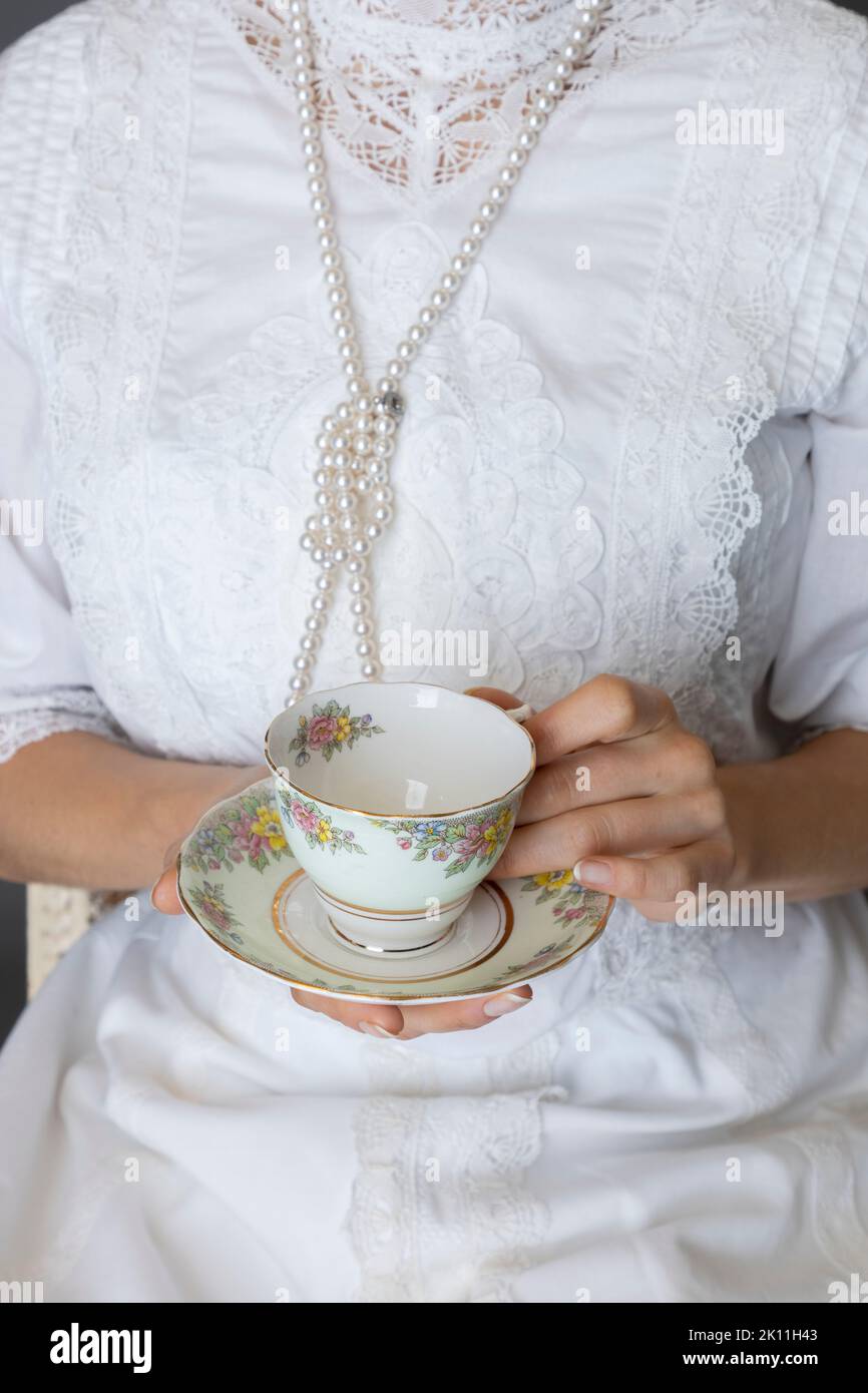 Eine edwardianische Frau mit weißer Spitzenbluse und Rock vor grauem Studiohintergrund Stockfoto