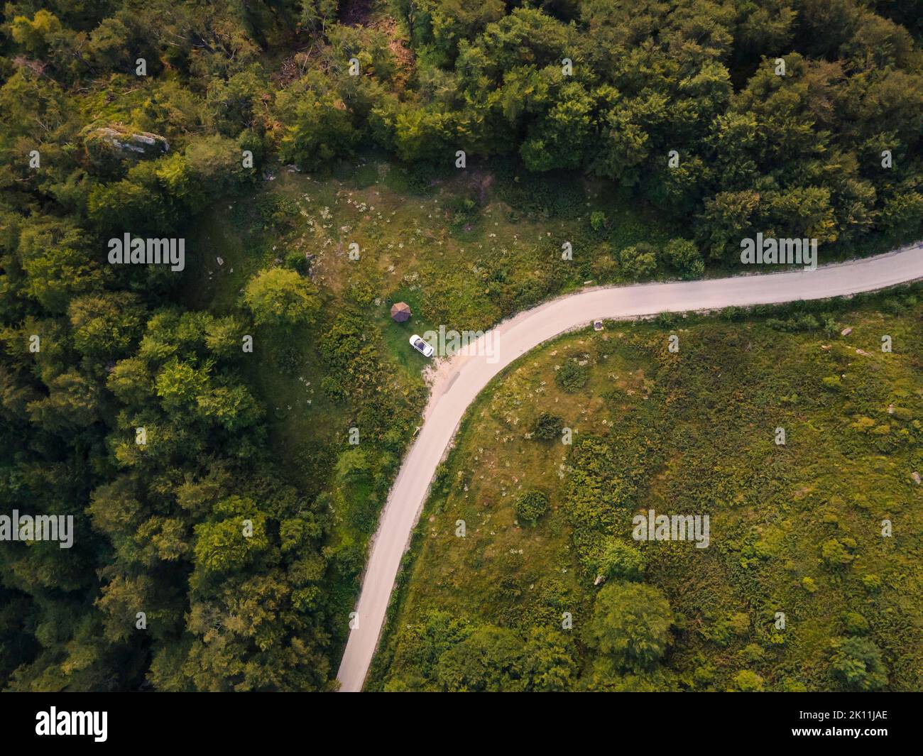 Top down Luftdrohne Blick auf die Straße in der Bergkette durch die Bäume und Wald und Auto geparkt wild reisen ländlichen Urlaub und Naturkonzept zurück Stockfoto