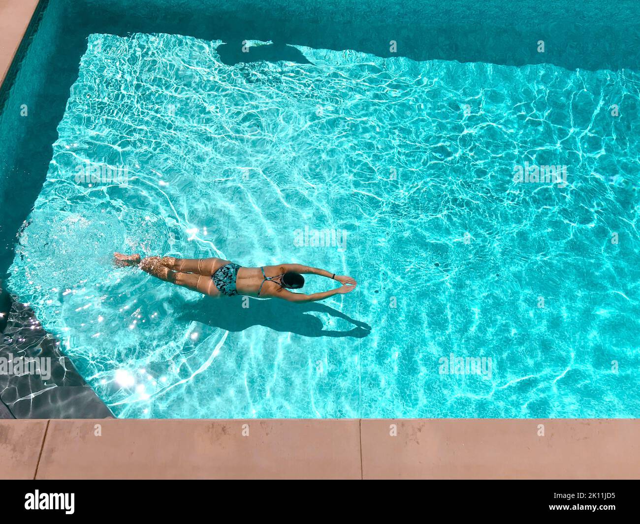 Frau schwimmt an einem sonnigen Tag mit dem Gesicht nach unten im Außenpool Stockfoto