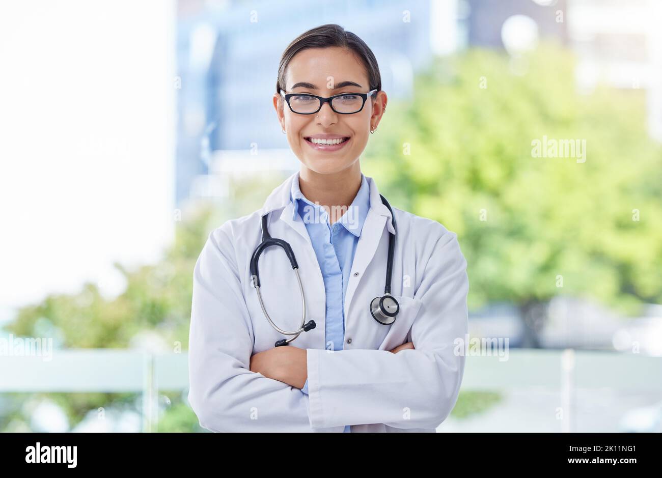 Gesundheitswesen, stolz und Arzt Frau Porträt mit Stethoskop in einem Krankenhaus mit Bokeh und Linse Flare. Pflege, Vertrauen und Mission eines jungen Arztes Stockfoto