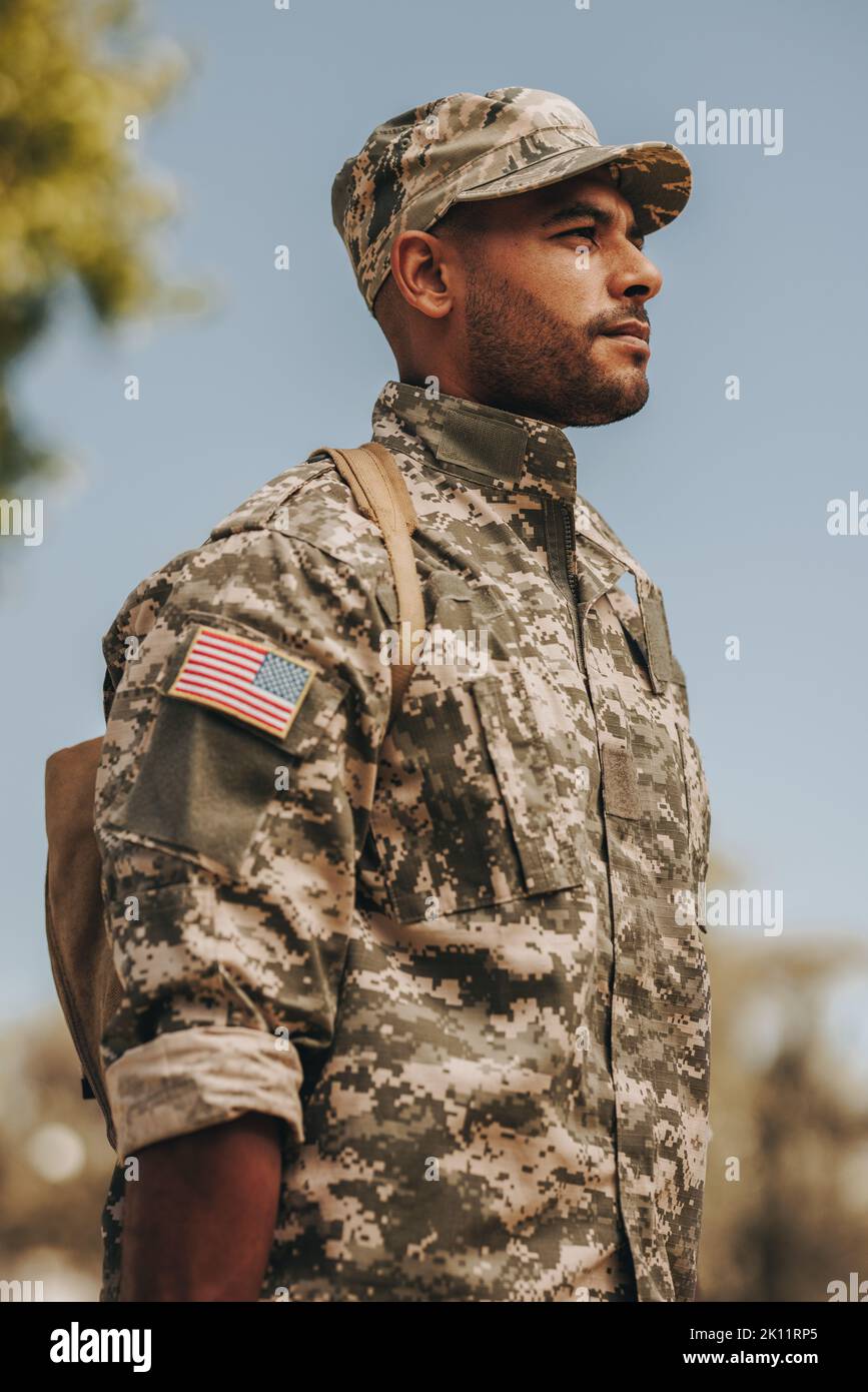 Patriotischer junger Soldat, der vor seinem Haus zur Aufmerksamkeit steht. Mutiger amerikanischer Militärangehöriger, der nach seinem Dienst in der Milit nach Hause zurückkehrt Stockfoto