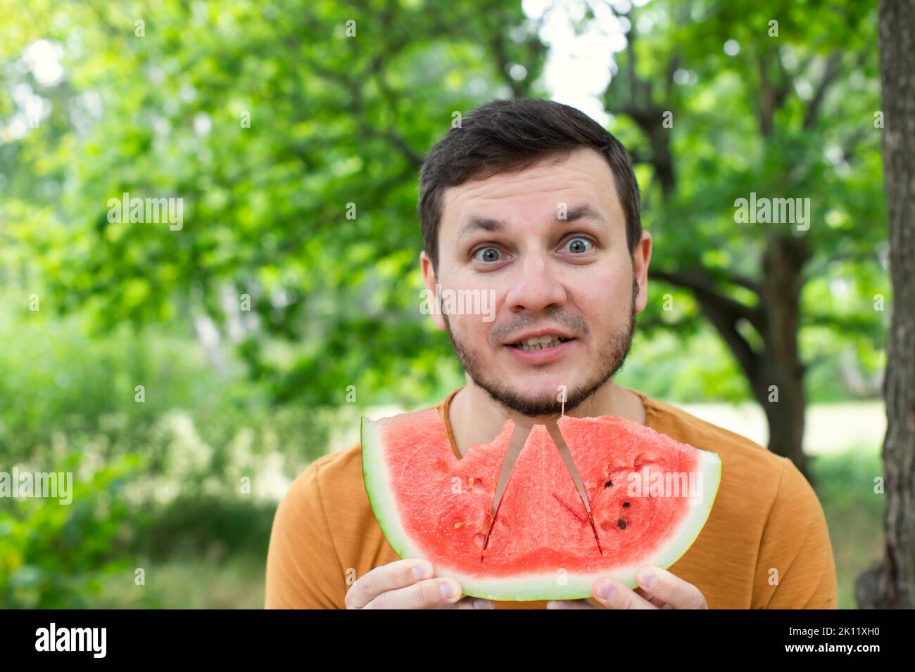 Mann, der saftige rote Wassermelone isst. Das Konzept von Sommer und köstlichem Gemüse. Vorderansicht. Stockfoto