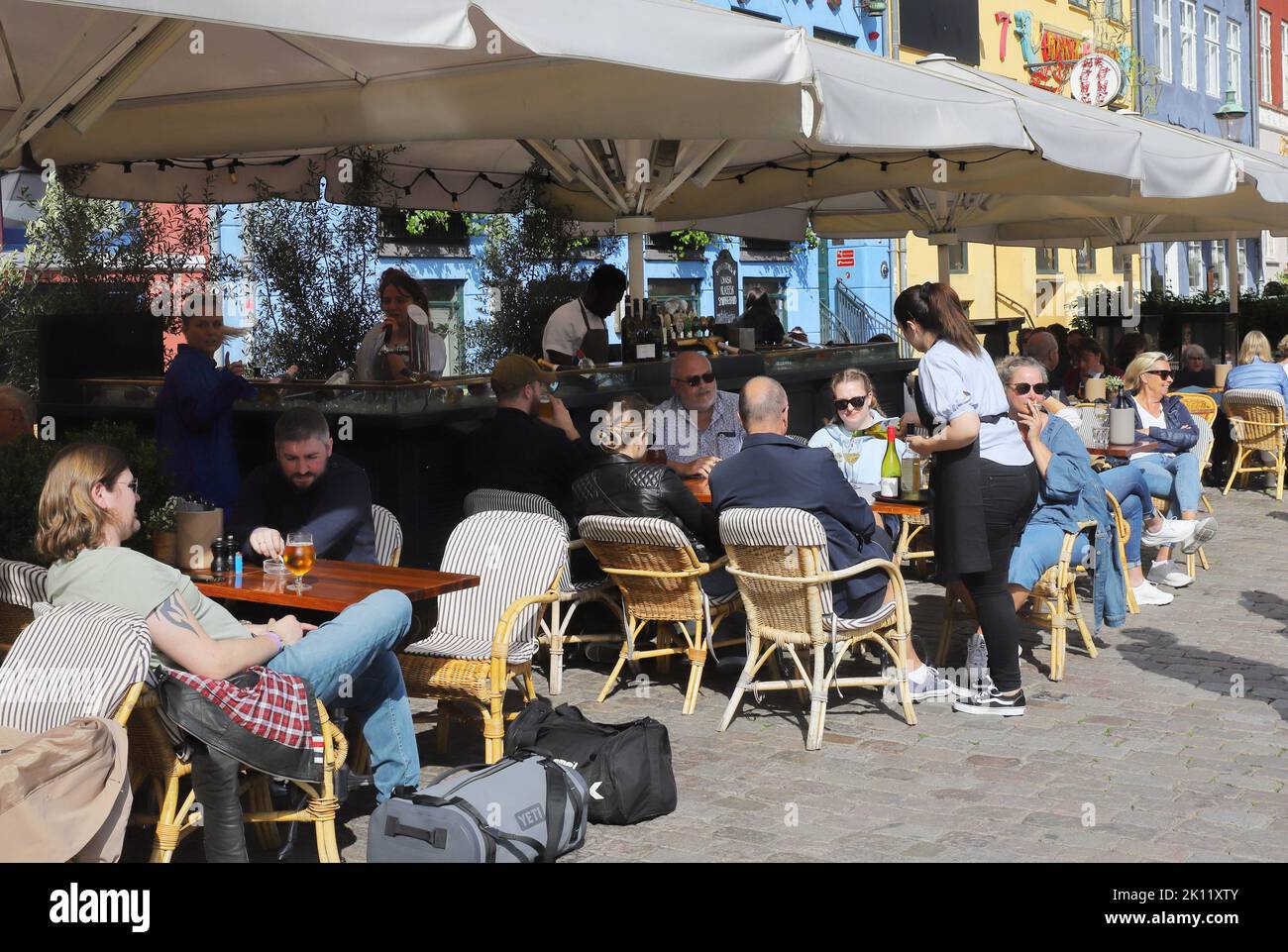 Kopenhagen, Dänemark - 14. Juni 2022: Restaurant mit Sitzgelegenheiten im Freien im Nyhavn-Bereich. Stockfoto