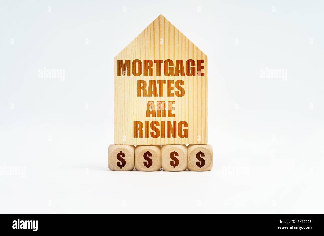 Immobilien und Geschäfte. Auf einer weißen Oberfläche steht ein Holzmodell eines Hauses mit der Aufschrift - die Hypothekenzinsen steigen Stockfoto