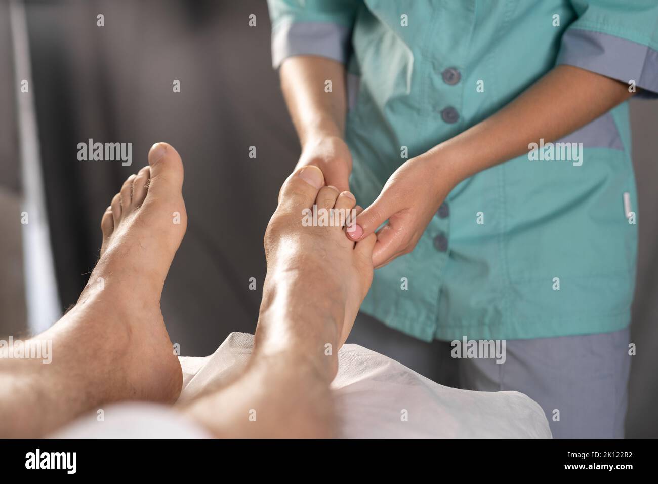 Mann mit Fußmassage im medizinischen Büro. Nahaufnahme eines Wellness-Profis bei einer Fußmassage im Salon Stockfoto