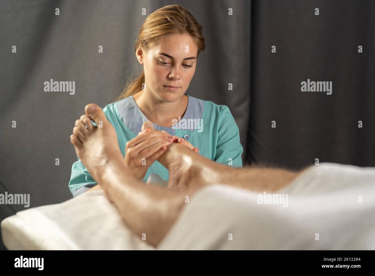 Mann liegt und bekommt Behandlung im Gesundheitszentrum. Masseuse Hände tun Massage auf müde Männer Füße. Erholsamer und erholsamer Tag. Professionelle Betreuung Stockfoto