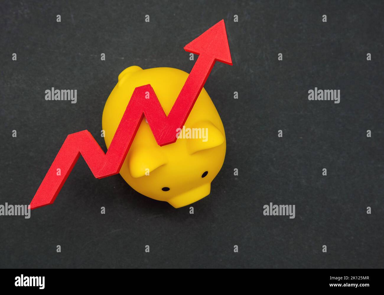 Inflation, Wirtschaftskrise, Sparkonzept. Kostenaufstieg Pfeil auf Sparschwein, schwarzer Hintergrund, Draufsicht Stockfoto