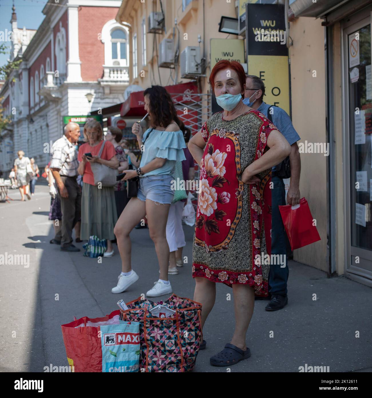 Belgrad, Serbien, 5. Aug 2022: Menschen auf dem Bürgersteig im Schatten warten auf einen Bus Stockfoto
