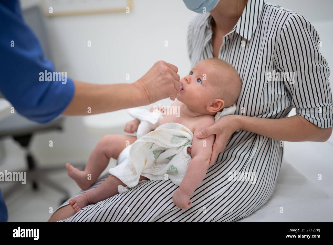 Kinderarzt, der in Anwesenheit seiner Mutter eine orale Impfung gegen Rotavirus-Infektion bei Kleinkind verabreicht. Gesundheitsversorgung und Krankheit von Kindern Stockfoto