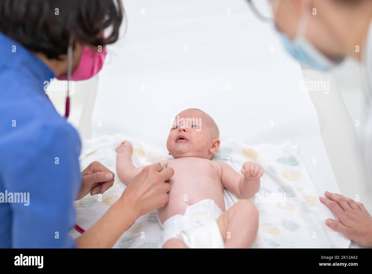 Baby liegt auf dem Rücken, als sein Arzt ihn untersucht Bei einer Standarduntersuchung Stockfoto