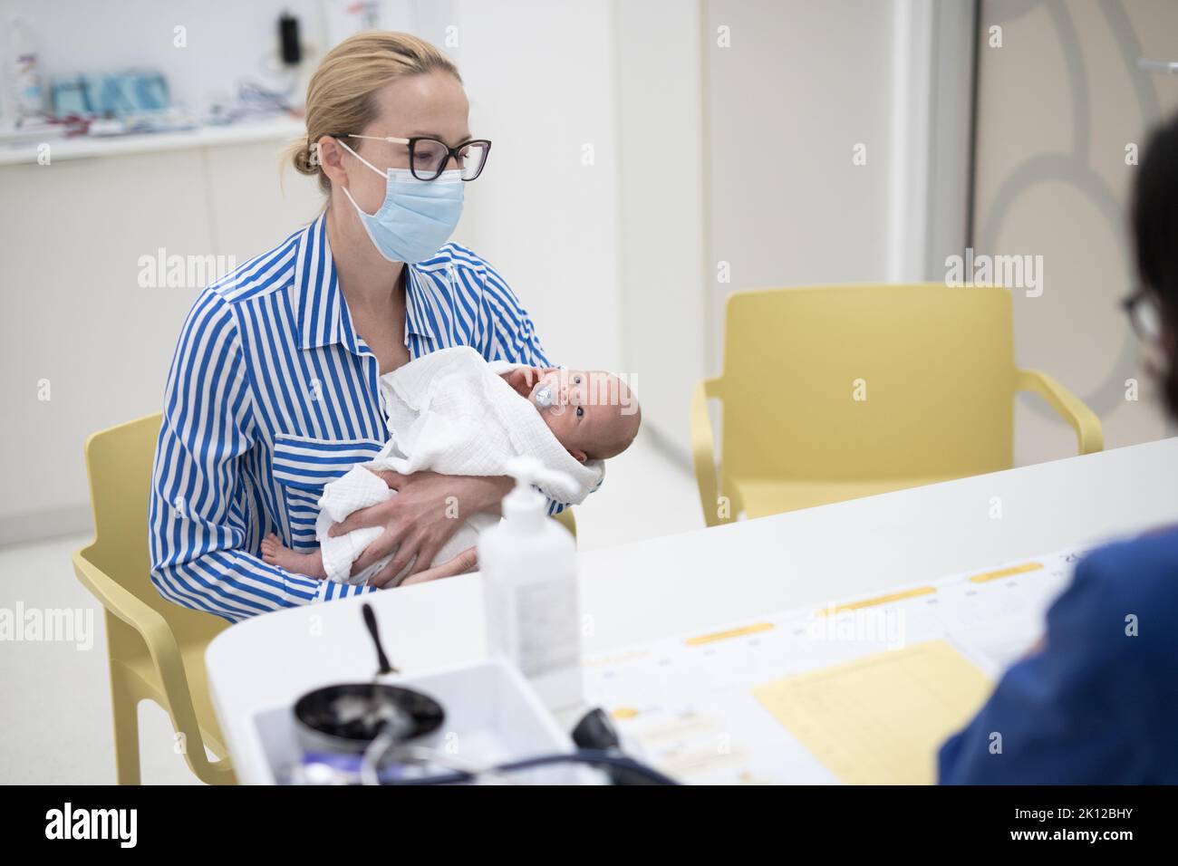 Mutter hält ihren Jungen bei einem medizinischen Termin im Kinderarztbüro. Stockfoto