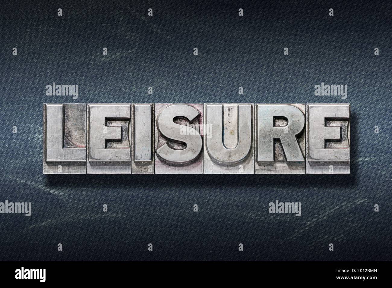 Freizeitwort aus Metallic-Buchdruck auf dunklem Jeans-Hintergrund Stockfoto