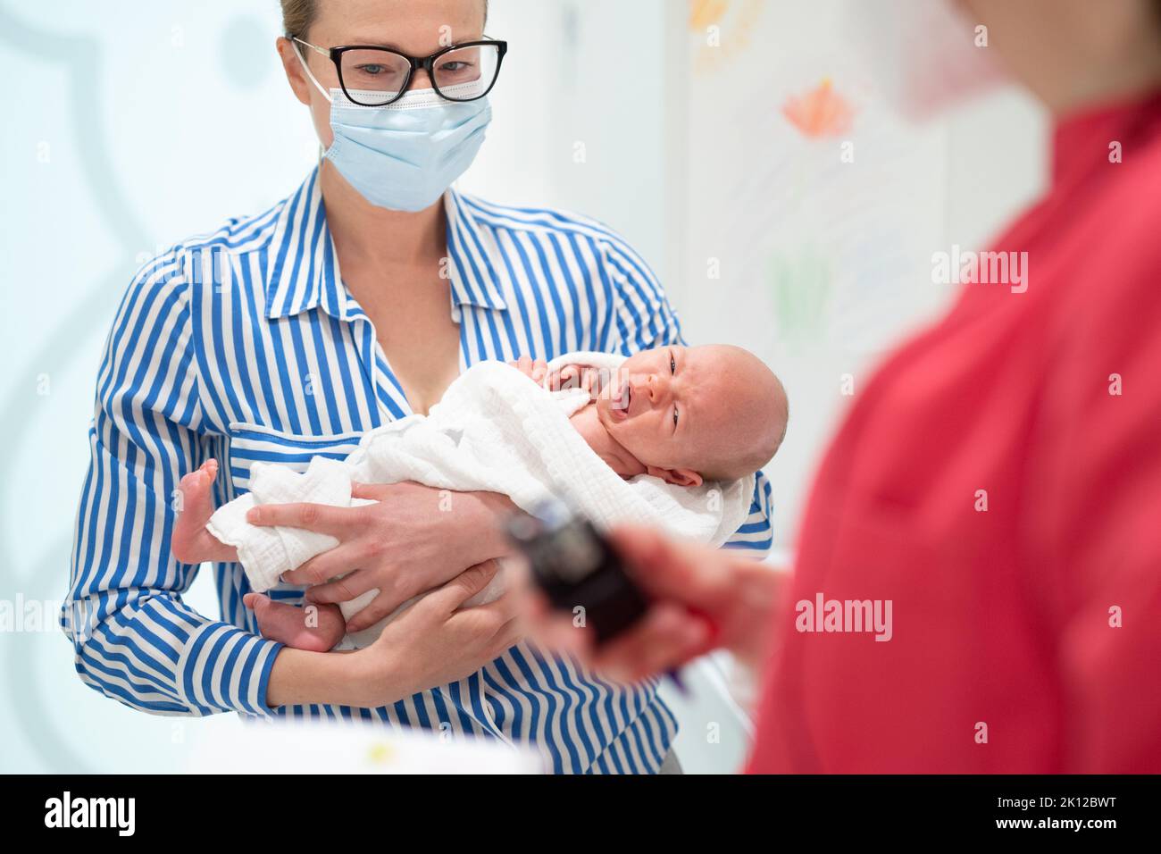 Mutter hält ihren Jungen bei einem medizinischen Termin im Kinderarztbüro. Stockfoto