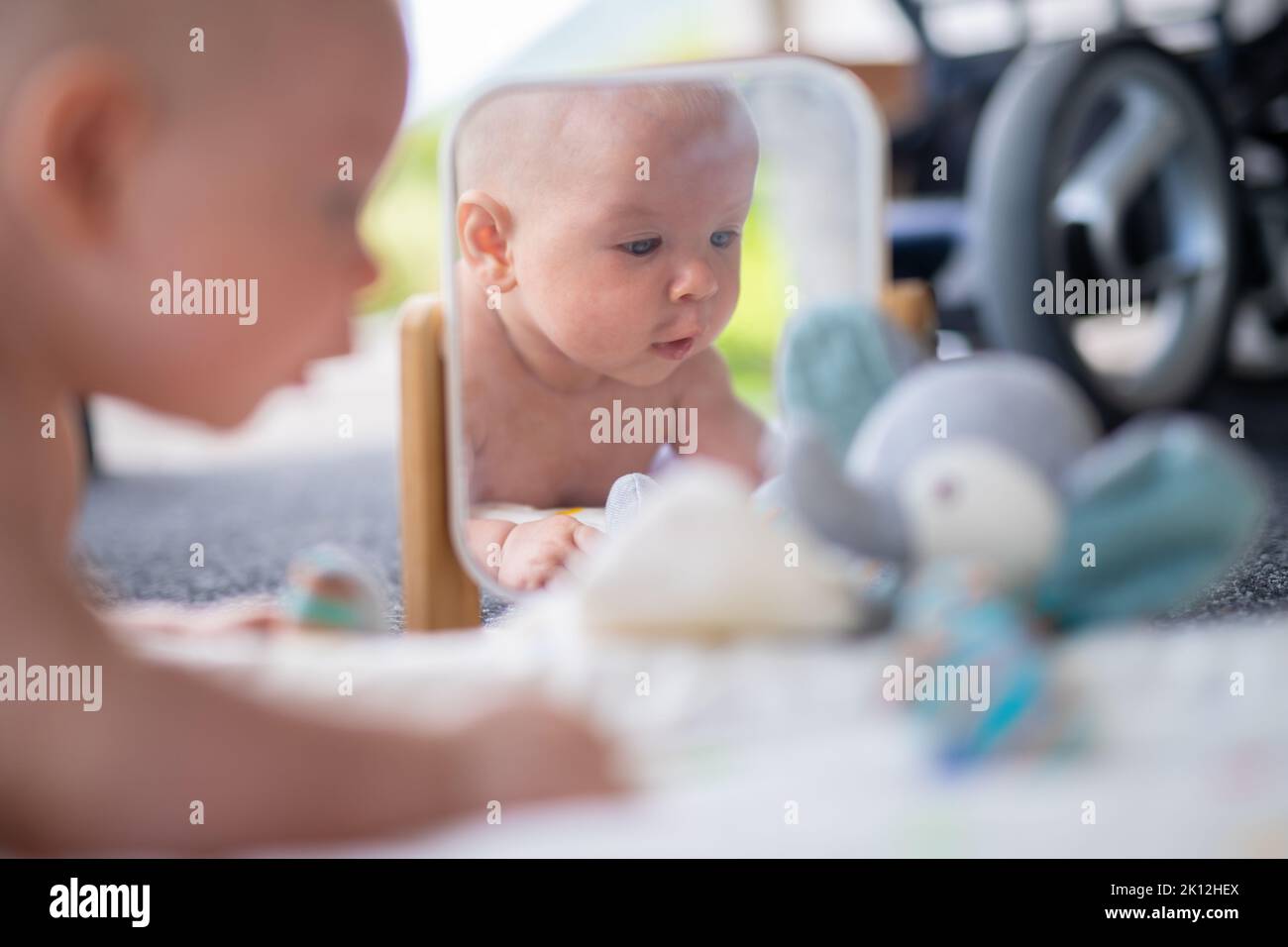 Schöne Aufnahme von Spiegel Reflectiona von niedlichen Baby Junge spielen mit Spielzeug. Stockfoto
