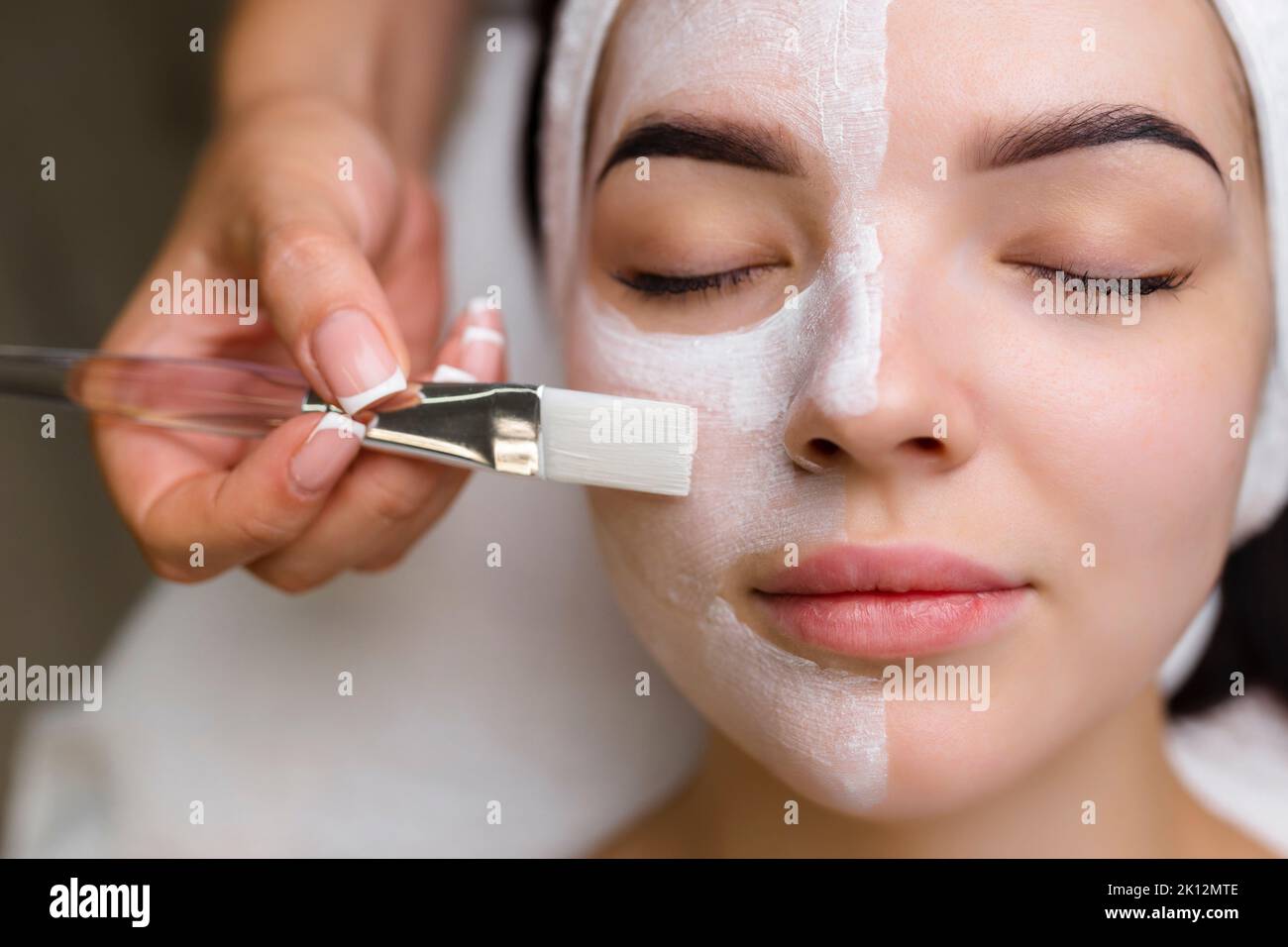 Nahaufnahme einer Frau, die eine Gesichtsbehandlung mit Tonmaske erhält. Kosmetologie und Spa Stockfoto