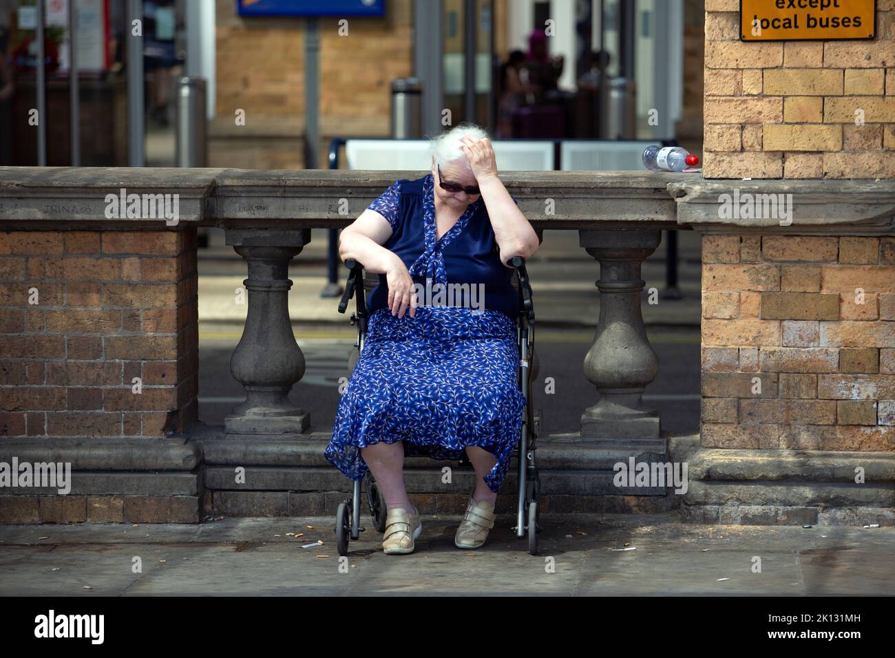 Eine ältere Frau, die an einer Bushaltestelle wartet, kämpft mit der Hitze, während die Menschen in der Stadt York, North Yorkshire, den heißesten Tag der Aufzeichnung aushalten Stockfoto