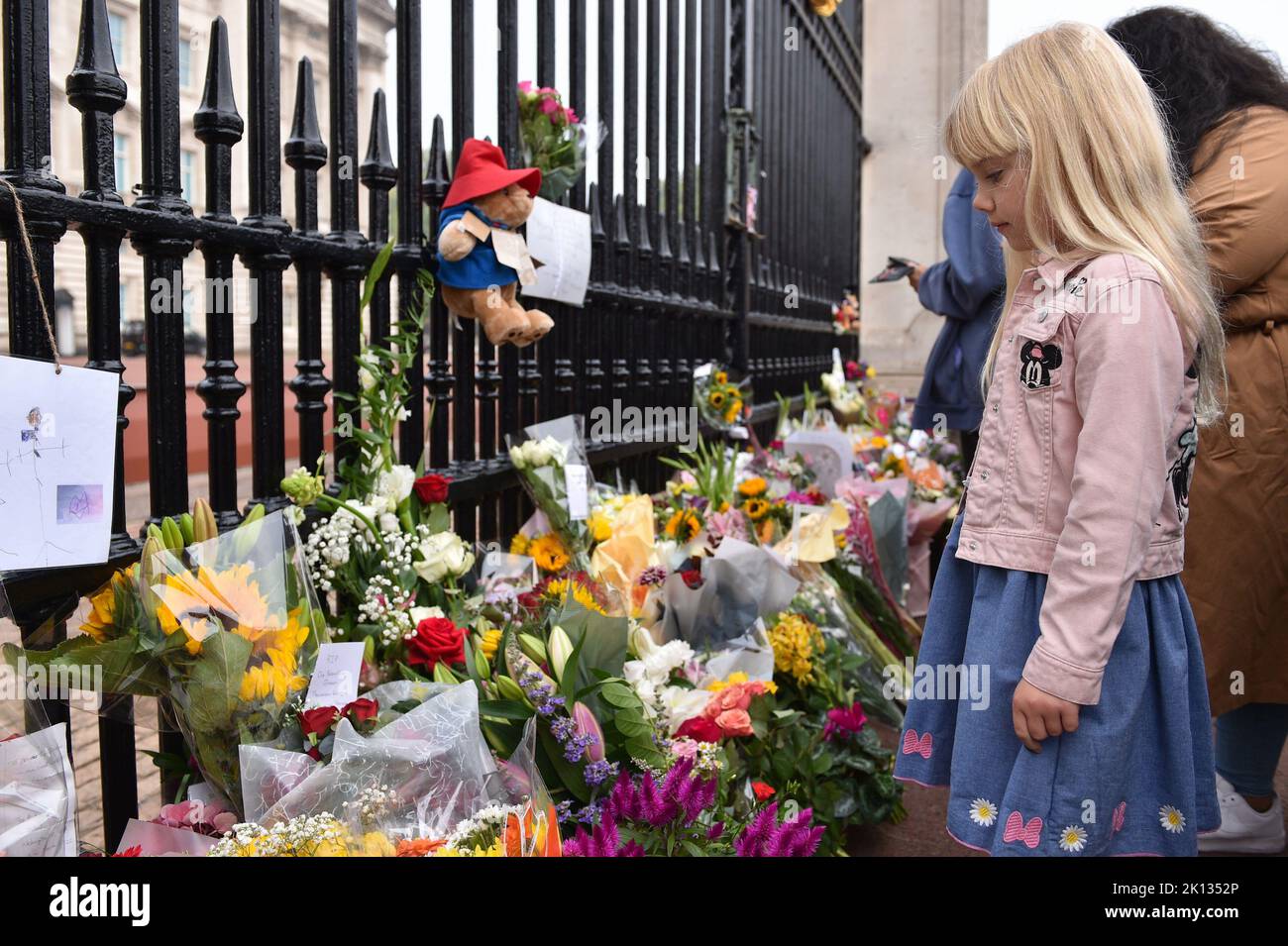 Ein Kind sieht sich die Blumenverehrungen an, die für Ihre Majestät Königin Elizabeth II. Im Buckingham Palace in London hinterlassen wurden. Stockfoto