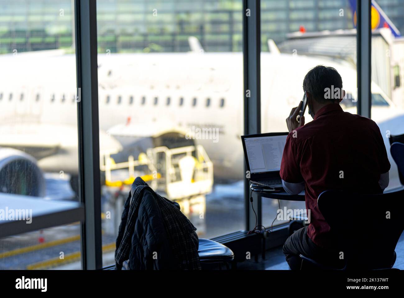Geschäftsmann, der am Flughafen, in Norwegen, Skandinavien und Europa am Laptop arbeitet und mit dem Mobiltelefon spricht Stockfoto