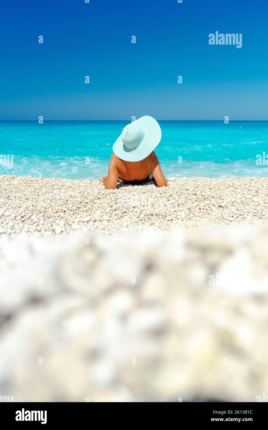 Frau mit Strohhut, die im Sommer das Meer am Strand betrachtet, Kefalonia, Ionische Inseln, griechische Inseln, Griechenland, Europa Stockfoto