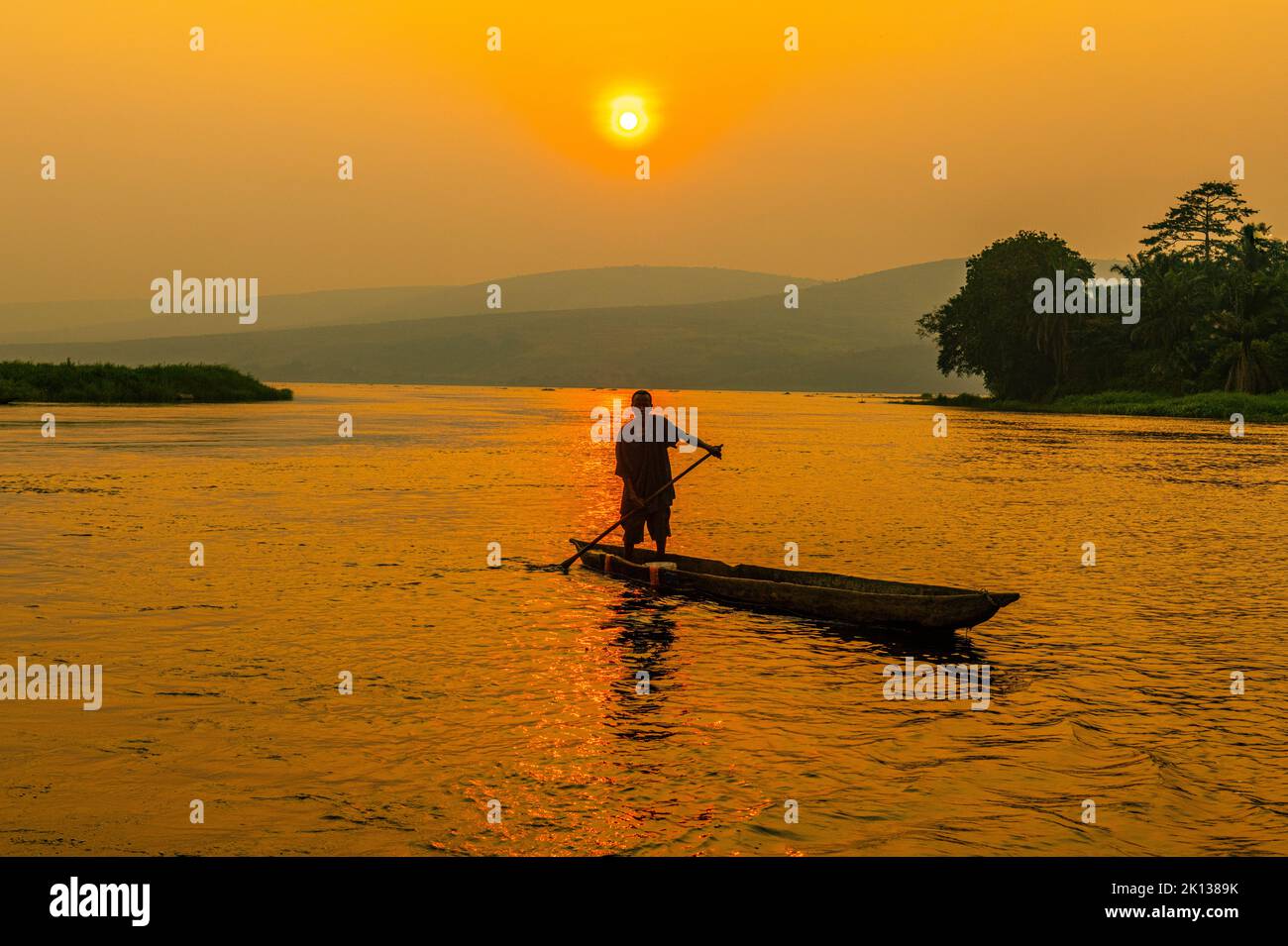 Mann auf seinem Ausgußkanu bei Sonnenuntergang auf dem Kongo-Fluss, Demokratische Republik Kongo, Afrika Stockfoto