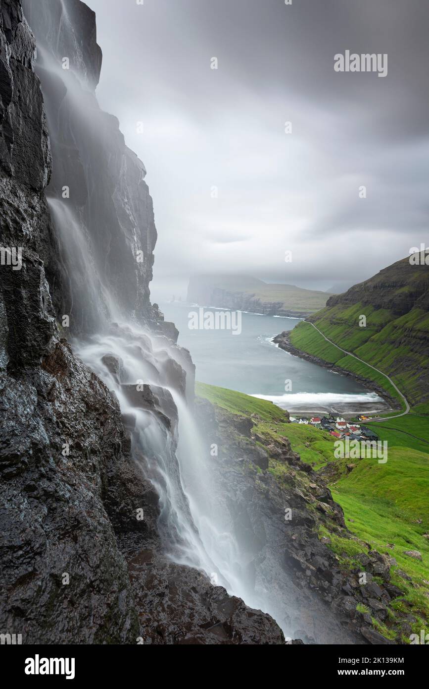 Nahaufnahme des Wasserfalls und des Dorfes Tjornuvik in der Abenddämmerung, Insel Streymoy, Färöer, Dänemark, Europa Stockfoto