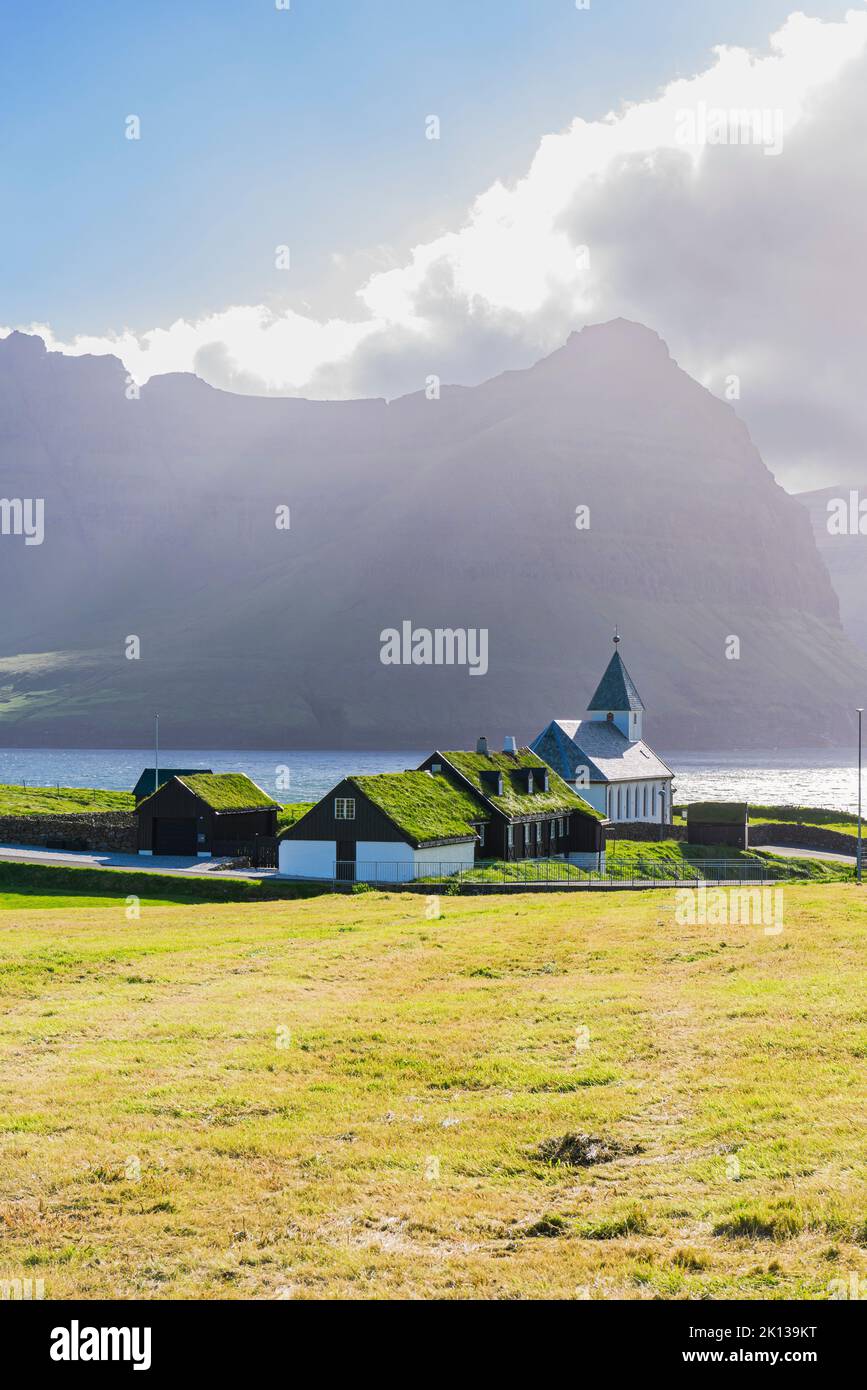 Blick auf die Kirche und die Grasdachhäuser im Dorf Vidareidi bei Sonnenuntergang, Vidoy Insel, Färöer Insel, Dänemark, Europa Stockfoto