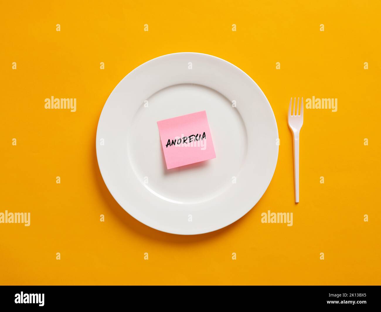 Notizbuch mit dem Wort Anorexie auf einem weißen Teller. Essstörung und ungesunde Ernährung Konzept. Stockfoto