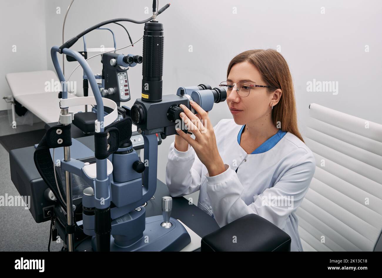 Porträt einer kaukasischen Optometristin in der Nähe von ophthalmologischen Geräten in der modernen Augenklinik. Augenheilkunde Stockfoto