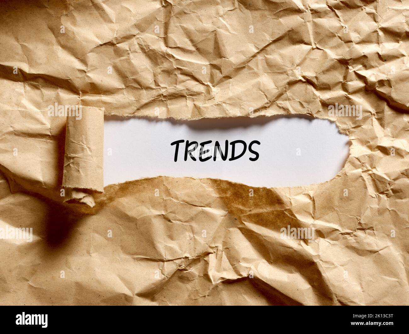 Das Wort Trends geschrieben unter einem braunen zerrissenen Papier. Entdecken Sie das aktuelle beliebte Trendkonzept. Stockfoto