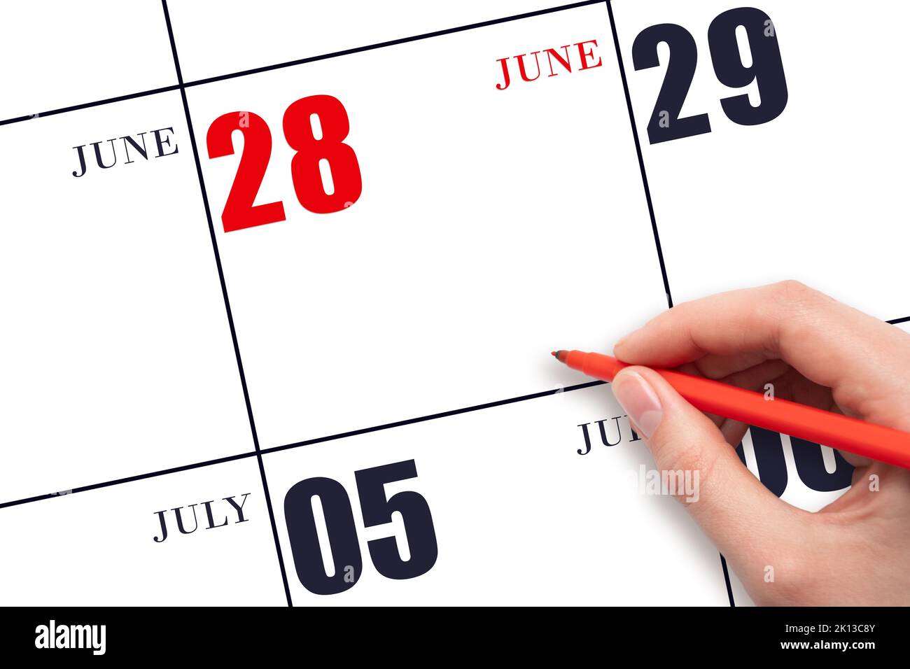 28. Tage im Juni. Eine Hand, die einen roten Stift hält und auf das 28. Tage im Juni. Eine Hand, die einen roten Stift hält und auf das