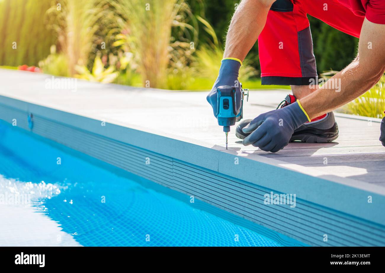 Kaukasischer Mann Gebäude Composite Swimming Pool Deck In Seinem Garten Im Garten. Nahaufnahme Des Bohrers. Stockfoto