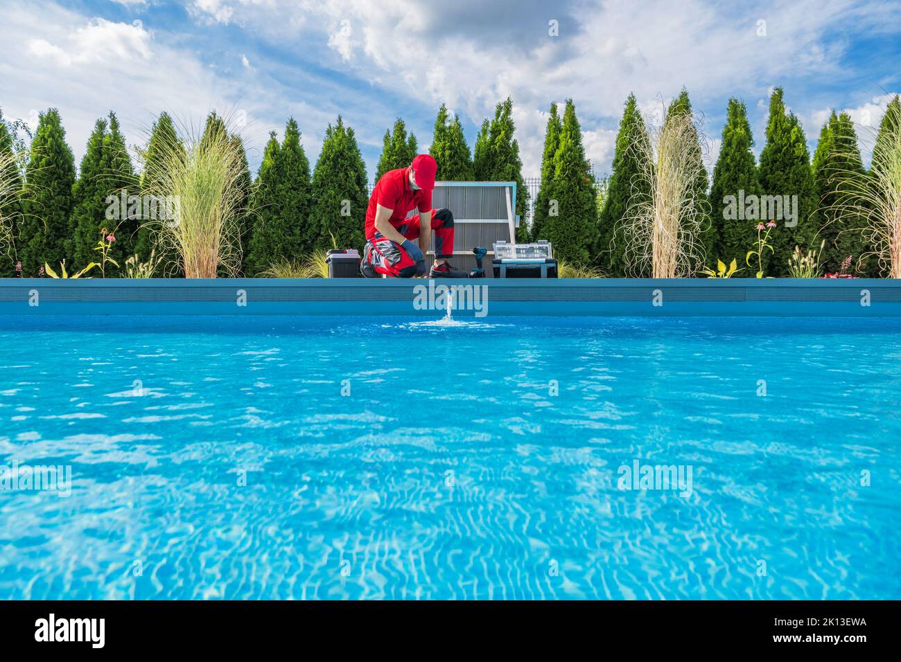 Professioneller Kaukasischer Schwimmbadtechniker in seinem Jahr 40s bei der Durchführung der saisonalen Wartung. Außenwohnanlage Mit Garten-Pool. Stockfoto