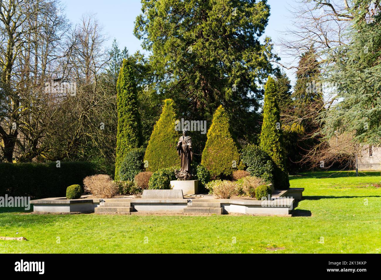 Ein grünes Gebüsch neben einer kleinen Skulptur im Maynooth University Park, Irland Stockfoto