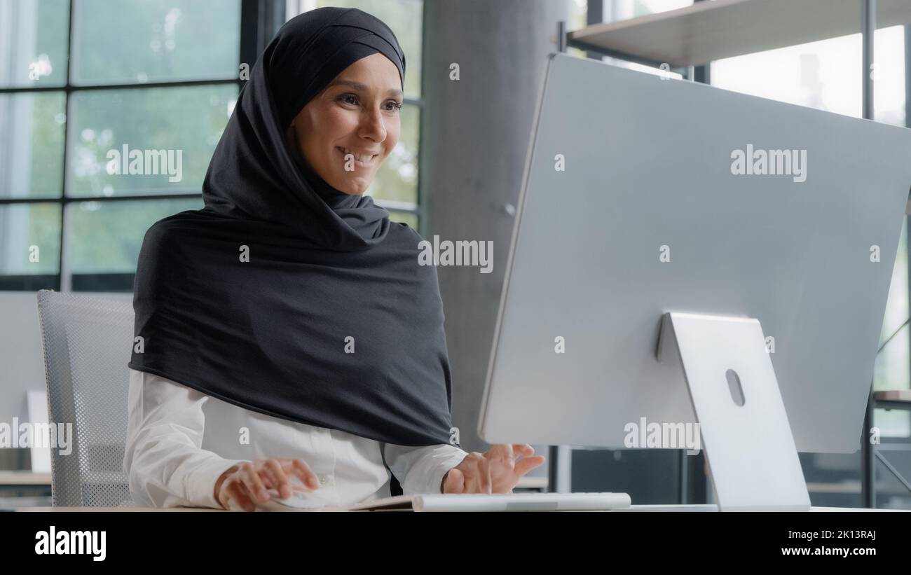 Junge arabische Geschäftsfrau in Hijab arbeitet am Computer lächelnd genießen Büroarbeit erfolgreiche Frau professionelle Manager Firma Mitarbeiter entwickelt Stockfoto