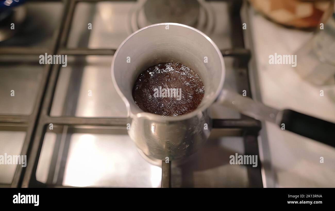 Türkischer Kaffee kocht über von CEZVE. Dichter Schaum in der Kaffeemaschine auf einem Gasherd. Stockfoto