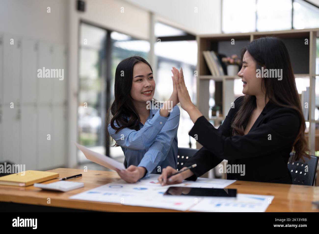 Zwei Personen begrüßen fünf gemeinsam für ihr erfolgreiches Geschäftsprojekt im Besprechungsraum. Zwei Geschäftsleute schauen sich gegenseitig an Stockfoto