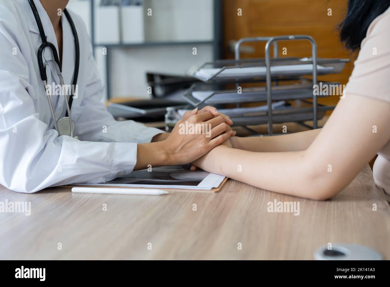 Nahaufnahme Arzt Trost Halten Sie die Hand Patient mit Röntgenstrahl in seinem Büro. Stockfoto
