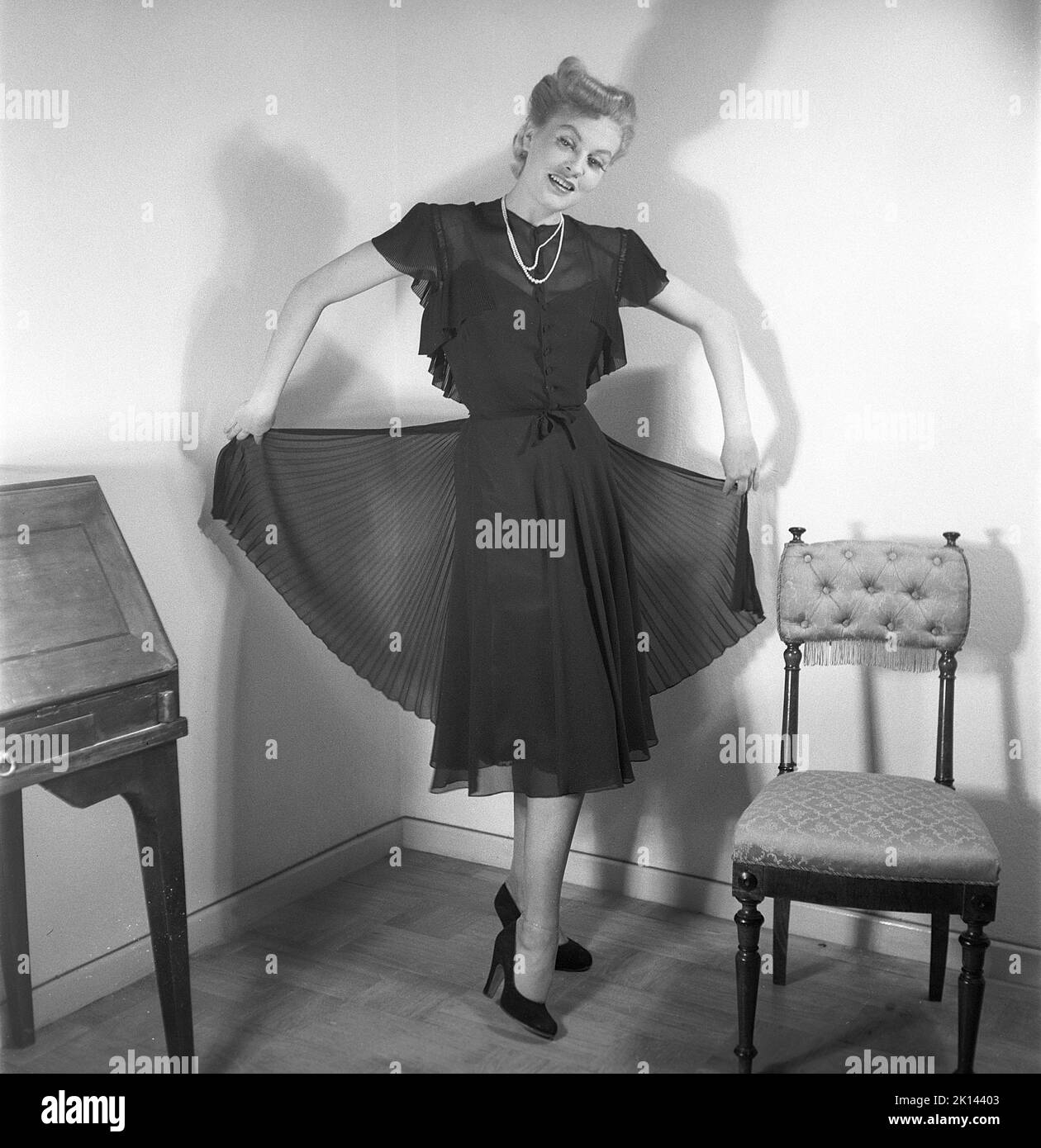 Damenmode im Jahr 1940s. Eine junge Frau, die für ein Damenmagazin fotografiert wurde, um die Damenmode von 1945 zu zeigen. Das weibliche Model trägt ein schwarzes Abendkleid in verschiedenen Stoffschichten. Schweden 1945. Kristoffersson Ref. R2-4 Stockfoto