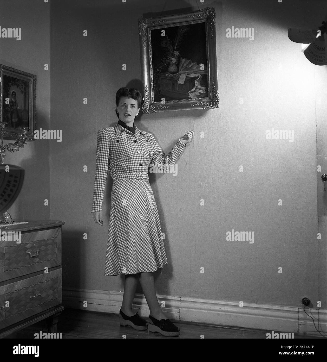 Damenmode im Jahr 1940s. Eine junge Frau, die für ein Damenmagazin fotografiert wurde, um die Damenmode von 1945 zu zeigen. Das weibliche Modell trägt ein kariertes gemustertes Kleid Sweden 1945. Kristoffersson Ref. R6-5 Stockfoto