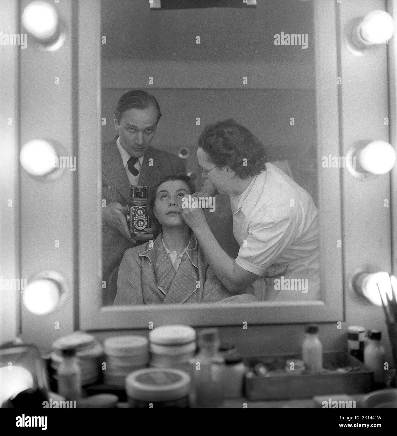 Make-up in der 1950s. Bevor sie am Filmset arbeitete, bekommt die Schauspielerin Maj-Britt Nilsson von einer Assistentin ein theatrales Make-up. Beachten Sie, dass sich der Fotograf im Spiegel selbst ins Bild einfügt. Schweden 1953 Kristoffersson Ref. BL42-3 Stockfoto