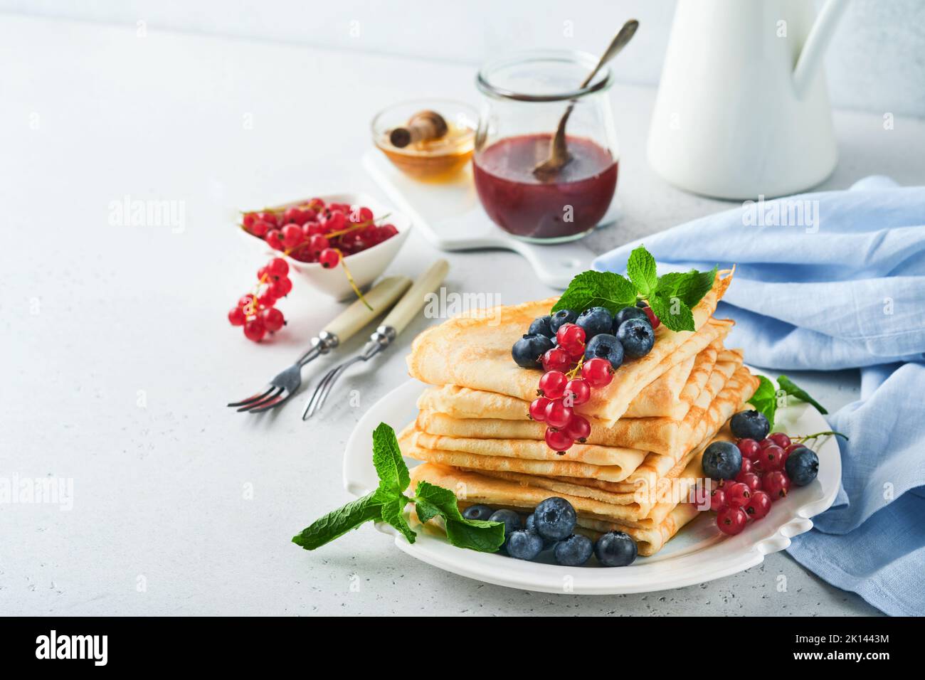 Pfannkuchen. Stapel von Crepes oder dünnen Pfannkuchen mit Beeren, Heidelbeeren, roten Johannisbeeren, Himbeeren und Honig zum Frühstück. Hausgemachtes Frühstück. Kopieren Sie den SPAC Stockfoto