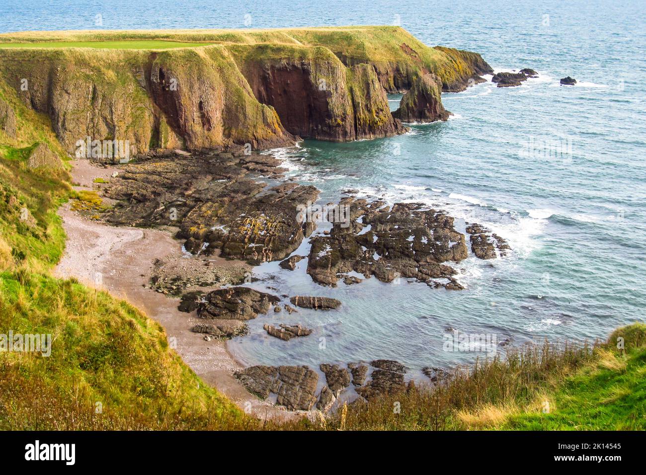 Geschützte Bucht zwischen den hohen Basaltklippen der nordschottischen Küste Stockfoto