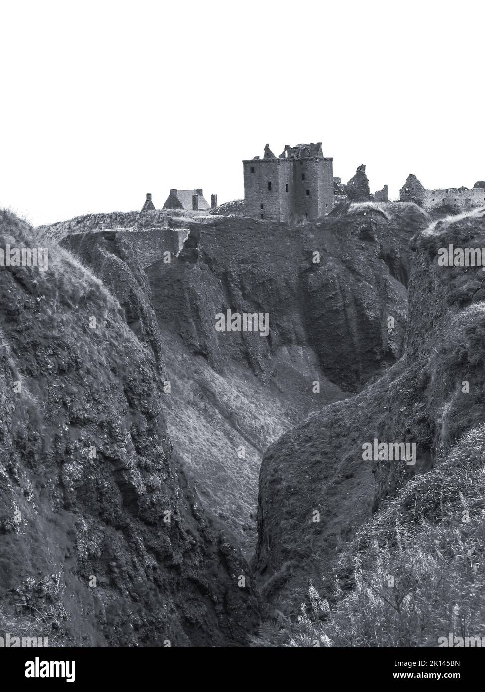 Blick über eine tiefe Schlucht mit den Ruinen einer mittelalterlichen schottischen Burg im Hintergrund. Stockfoto