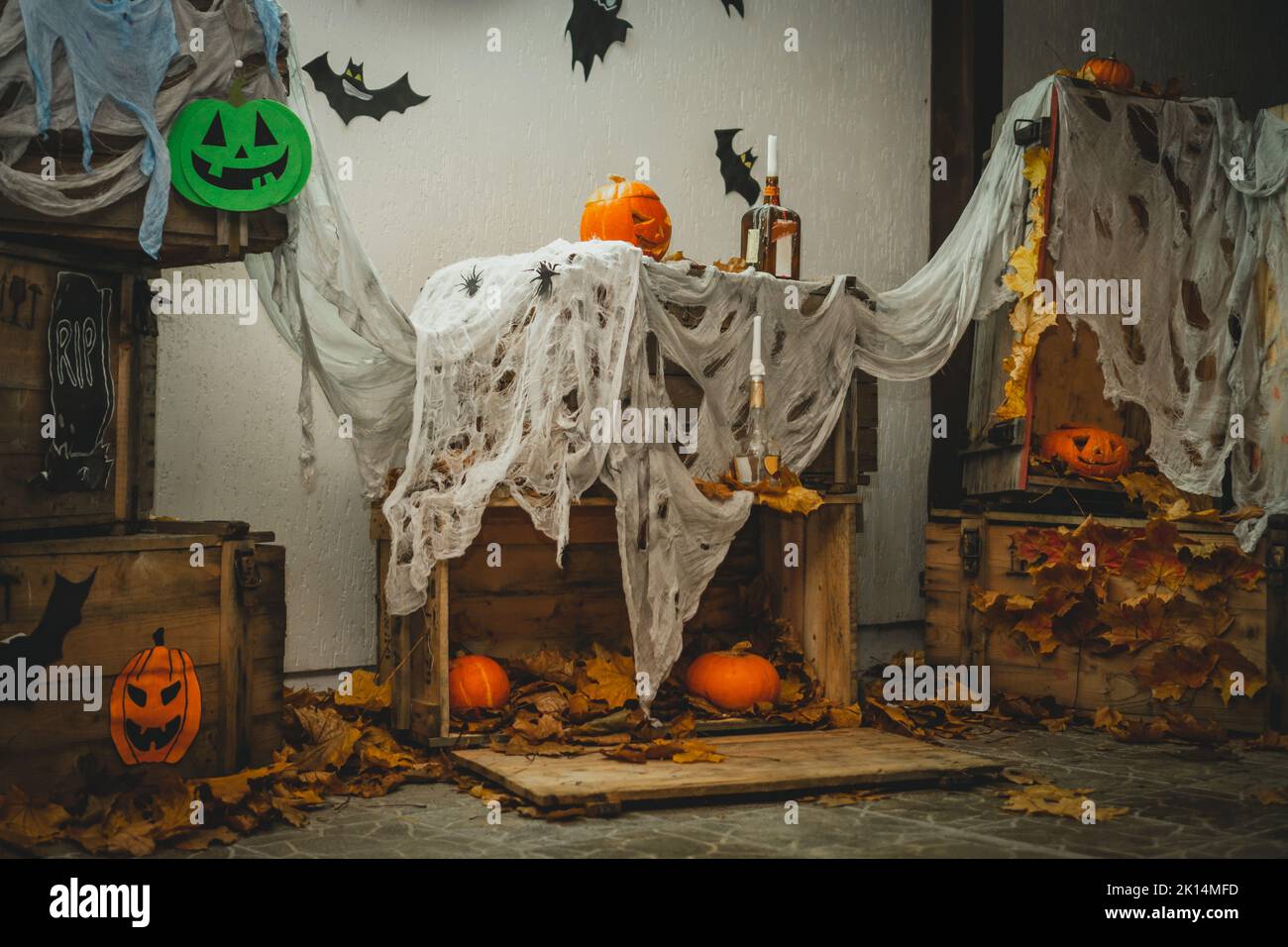 DIY Halloween Gartendekoration mit orange hellen halloween Kürbissen mit geschnitzten Nase, Mund und Augen und Holzkisten mit Gaze als Netz, Fledermäuse und Stockfoto