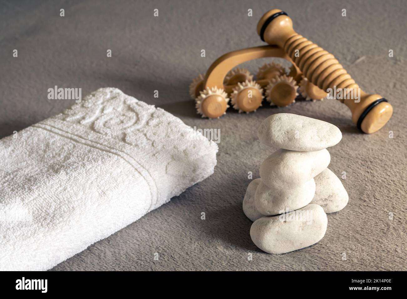 Zen-Spa-Komposition, gestapelte weiße Steine, Massagegeräte und Handtücher Stockfoto